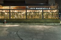 a building on a sidewalk in a neighborhood with christmas lights in the window frames outside