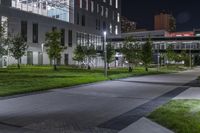 the green grass on the street is illuminated by lights of different size and shape in the buildings