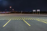 an empty parking lot with an illuminated sky in the background in a city at night