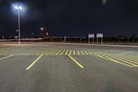 an empty parking lot with an illuminated sky in the background in a city at night