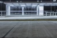 a deserted parking lot lit up by street lamps at night with one man walking by the bench