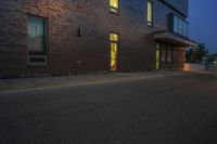 the street has a curb and some light at night, with a building on it