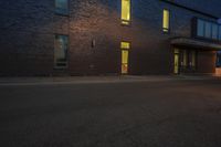 the street has a curb and some light at night, with a building on it