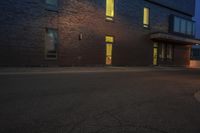 the street has a curb and some light at night, with a building on it