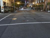 a deserted city street filled with traffic at night time at dusk, with lights on