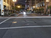 a deserted city street filled with traffic at night time at dusk, with lights on