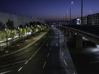 the highway is lined with traffic lights at night time and surrounded by an airport fence