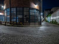 some dark blue windows in an industrial building with no one on the street to the right