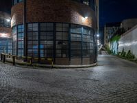 some dark blue windows in an industrial building with no one on the street to the right