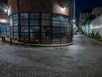 some dark blue windows in an industrial building with no one on the street to the right