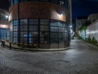 some dark blue windows in an industrial building with no one on the street to the right