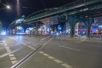 an empty city street is lit with lamps, people and a pedestrian crossing over the bridge