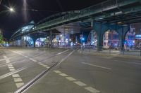 an empty city street is lit with lamps, people and a pedestrian crossing over the bridge