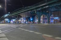 an empty city street is lit with lamps, people and a pedestrian crossing over the bridge