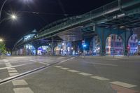 an empty city street is lit with lamps, people and a pedestrian crossing over the bridge