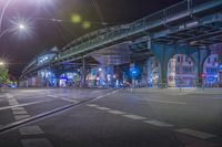 an empty city street is lit with lamps, people and a pedestrian crossing over the bridge