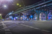 an empty city street is lit with lamps, people and a pedestrian crossing over the bridge