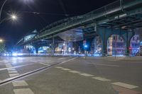 an empty city street is lit with lamps, people and a pedestrian crossing over the bridge