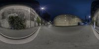 a wide angle photo shows the street lights, buildings and street curbs at night