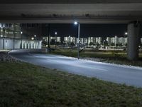 an empty street in an urban setting lit up at night under the highway overpass