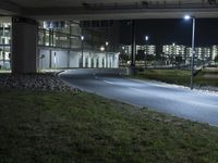 an empty street in an urban setting lit up at night under the highway overpass