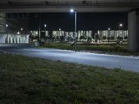 an empty street in an urban setting lit up at night under the highway overpass