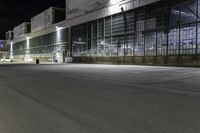 empty parking lot at night in front of large glass building at the corner of the street