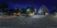 a fisheye lens shows an old building and empty street at night with lots of light on