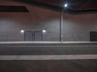 two empty benches and one has four lights on them at night on the side of a building