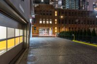 an alleyway with buildings at night, lit up by street lights, with a neon light in the distance