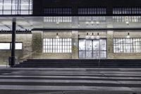 the front of a building lit up at night with stairs going to the door and a clock in the front