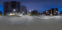 a photo of an urban street intersection at night, shot from fish eye lens with a camera