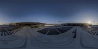 a 360 - angle photo of an airport parking garage by night with several people at the end