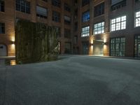 the large sculpture stands outside of a brick building by night in the dark lighted courtyard