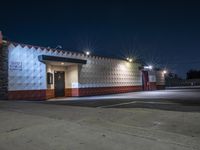 an empty store is lit up by street lights at night, with concrete walls in the foreground