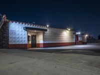 an empty store is lit up by street lights at night, with concrete walls in the foreground