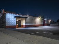 an empty store is lit up by street lights at night, with concrete walls in the foreground