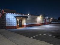 an empty store is lit up by street lights at night, with concrete walls in the foreground