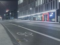 the empty city road is empty by the tall building in the background at night with light streaking on the buildings