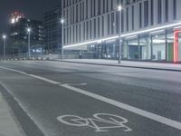 the empty city road is empty by the tall building in the background at night with light streaking on the buildings