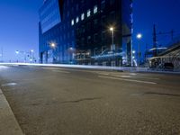 an empty city street and lights and a building with glass doors on both sides of the street