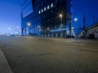 an empty city street and lights and a building with glass doors on both sides of the street