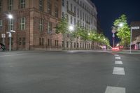 street light in night time with street view of buildings and cars driving on road and trees lining street