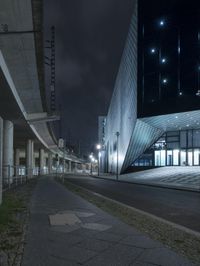 an empty street near a large modern structure at night's edge in a european country