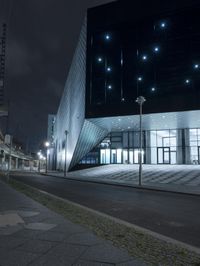 an empty street near a large modern structure at night's edge in a european country