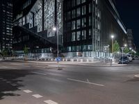 a road in front of tall buildings with lights on at night time in an urban area