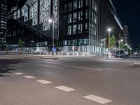 a road in front of tall buildings with lights on at night time in an urban area