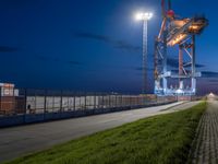 large, long dock on grassy area at night by a street with street lights lit up