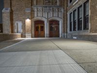 a street light is lit on a brick building near a sidewalk and a fire hydrant