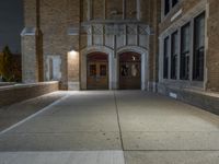 a street light is lit on a brick building near a sidewalk and a fire hydrant